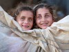 Two children peer out of a canvas tent