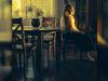 A woman sits in a chair looking at the floor with melancholy
