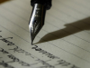 A pen hovers above lined paper with words (text unimportant) preceding