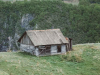 A photograph of an old house on a grassy hilltop
