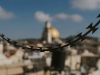 Jerusalem hangs out of focus in the background as a chain hangs across the image in the foreground