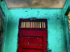 A photograph of a red door inset into a wall that has no roof, with the sky glowering in green-orange above