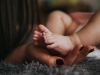 A close up photograph of a mother holding her baby's feet