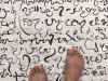 Bared feet standing on a cloth covered in a non-English script.