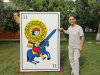 Youssouf Amine Elalamy standing next to a human sized playing card. He points to the tip of a sword.