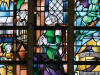 A photograph of a stained glass window featuring a number of figures praying