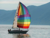 A sailboat with a rainbow sail on a lake