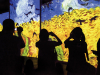 Figures in shadow look at paintings by Vincent van Gogh projected on video screens