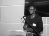 A black and white photograph of Maky Madiba Sylla speaking at a lectern