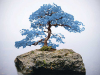 A photograph of a blue bonsai on a rock emerging from the water and surrounded by fog