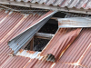 A photograph of a corrugated tin roof, partially peeled back