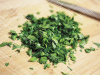 A pile of freshly chopped parsley on a knife-scarred cutting board