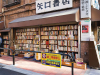 A Japanese salaryman pauses at a bookstall on the corner of two intersecting streets