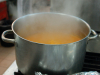 A photograph of a pot of broth steaming on a white stove