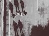 Three youths photographed from above, their shadows producing three upright figures trailing behind them