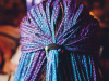 A photograph of the back of a person's head. They have tight braids, the outer layer of which dyed blue and purple