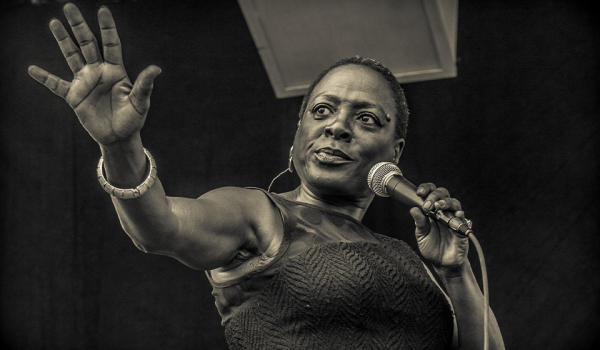 A photograph of Sharon Jones singing
