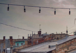 A photograph of a string of unlit lamps strung above an urban landscape