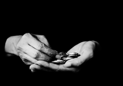A black and white photograph of a hand holding coins