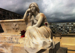 A statue of a reclining figure in a cemetery