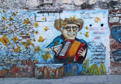 A photograph of a mural depicting a cartoonish drawing of Gabriel Garcia Marquez playing an accordion