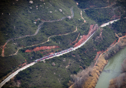 A distant shot of a train winding its way through a mountainous countryside