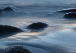 A photograph of rocks, mostly submerged in the tide