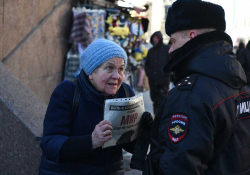A photograph of an elderly woman holding a pamphlet confronting a police officer