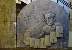 A stone sculpture of Ismail Kadare surrounded by books