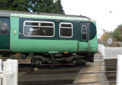 Green train passing platform outside