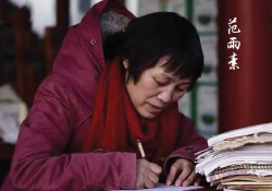 A photograph of a woman in a heavy red parka, hunched over a desk, writing